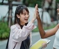 Two young female, one asian students share high 5 hand shake